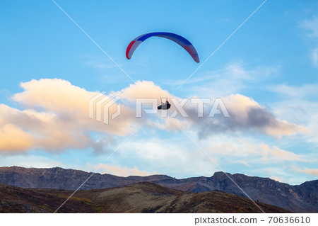 Paraglider flying over Scenic Mountain Range in Canadian Nature 70636610