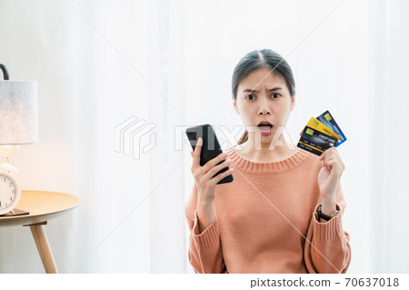 Shocked excited Asian woman holding credit card and smartphone, Because a lot of expenses. 70637018