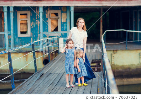 mom and kids in blue clothes standing old bridge 70637025