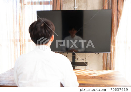 A man spending time watching TV in the room A man spending time watching TV in the room 70637419