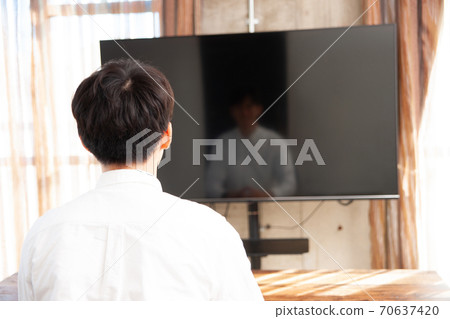 一個男人花時間在房間裡看電視 一個男人花時間在房間裡看電視 70637420