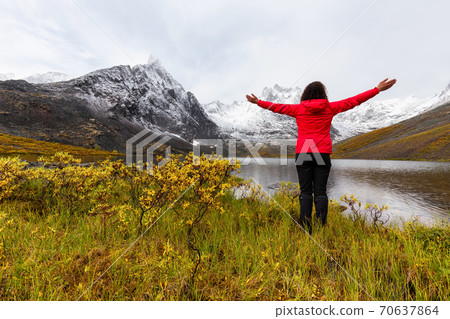 Woman standing with Arms up at Beautifil Alpine Lake Woman standing with Arms up at Beautifil Alpine Lake 70637864