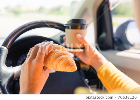 woman eating food fastfood and drink coffee while driving the car woman eating food fastfood and drink coffee while driving the car 70638120