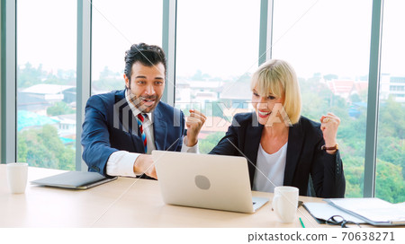Two happy business people celebrate at office Two happy business people celebrate at office 70638271