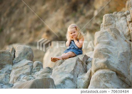 little girl sitting on rock at sunset. travel. 70638484