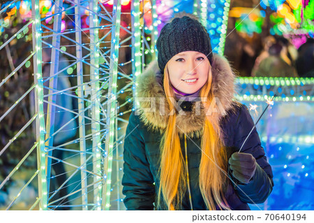 Portrait of young attractive celebrating woman holding sparkles. Crazy 2020 is over, it's 2021 70640194