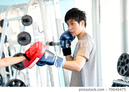 Young man hitting a mitt in the gym Young man hitting a mitt in the gym 70640475