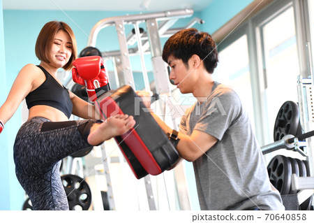 A woman and a trainer kicking a mitt 70640858