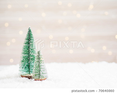Christmas trees in the foreground in artificial snow and a blurred background with glowing garland 70640860