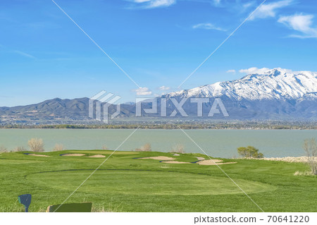 Scenic view of lake and grassy field under blue sky on a sunny day Scenic view of lake and grassy field under blue sky on a sunny day 70641220