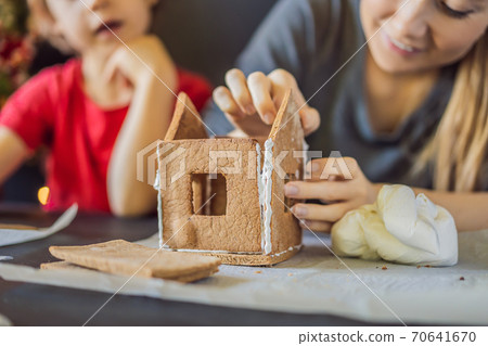 Young mother and kid making gingerbread house on Christmas eve 70641670
