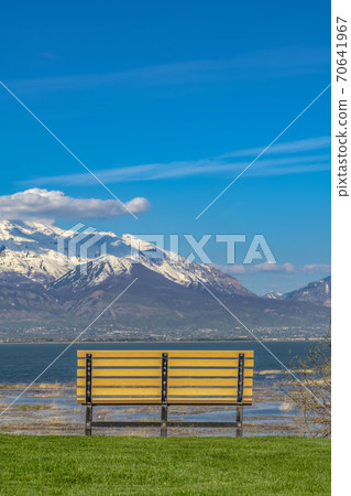 Close up of the bench on a grassy field in front of a lake on a sunny day 70641967