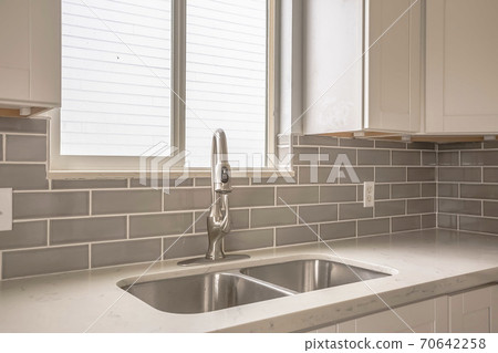 Undermount double bowl sink and faucet on the gleaming white kitchen countertop Undermount double bowl sink and faucet on the gleaming white kitchen countertop 70642258