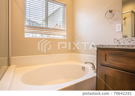 Bathroom interior with oval bathtub against white wall and window with blinds Bathroom interior with oval bathtub against white wall and window with blinds 70642281