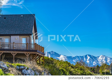 House on a hill with balcony overlooking snowy mountain and bright blue sky 70642293