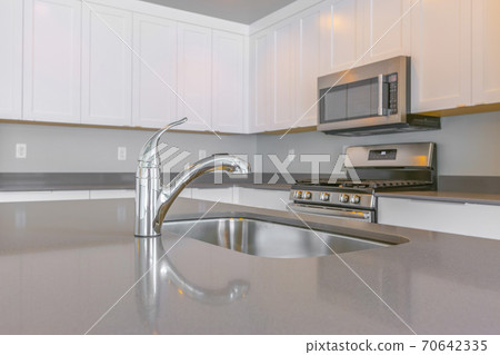 Close up of a glossy countertop with faucet and sink inside a modern kitchen 70642335