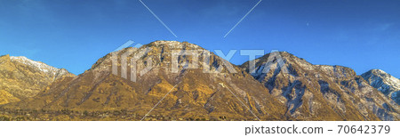 Towering mountain with a residential area near the base against deep blue sky 70642379