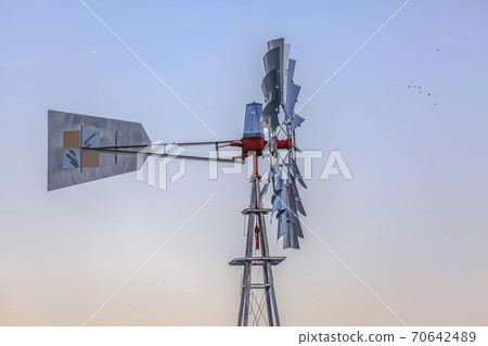 Side view of a windpump with the blades and tail connected to a red rotor hub. Side view of a windpump with the blades and tail connected to a red rotor hub. 70642489