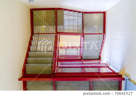 Flight of stairs viewed from the bottom floor inside a building with white wall Flight of stairs viewed from the bottom floor inside a building with white wall 70642527