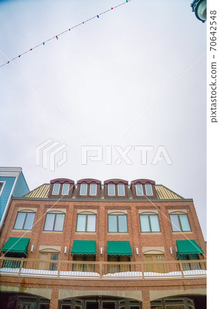 Cloudy sky and string lights over a building with brick wall and snowy balcony Cloudy sky and string lights over a building with brick wall and snowy balcony 70642548