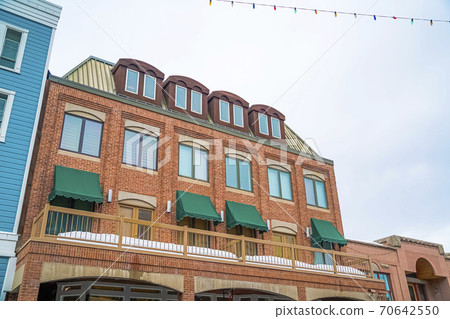 Exterior of a red brick building with green awnings on the balcony windows Exterior of a red brick building with green awnings on the balcony windows 70642550