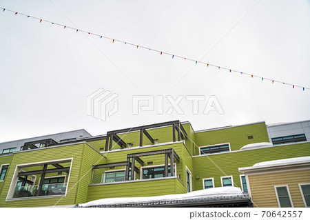 Building with green horizontal siding and balconies with glass railings Building with green horizontal siding and balconies with glass railings 70642557