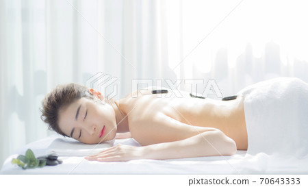 Beautiful woman lying down and receiving a massage 70643333