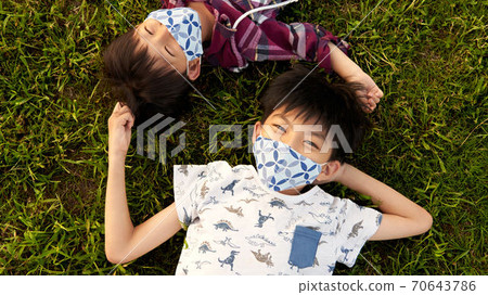 Boy in a mask lying on the grass 70643786