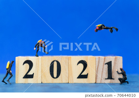 Miniature divers diving around wooden block 2021 , Happy new Year concept Miniature divers diving around wooden block 2021 , Happy new Year concept 70644010
