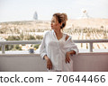 young beautiful Asian girl in beige lace shorts,white shirt drinking coffee standing on the balcony. selective focus. small focus area. 70644466