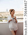 young beautiful Asian girl in beige lace shorts,white shirt drinking coffee standing on the balcony. selective focus. small focus area. 70644467