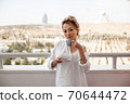 young beautiful Asian girl in beige lace shorts,white shirt drinking coffee standing on the balcony. selective focus. small focus area. 70644472