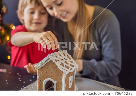 Young mother and kid making gingerbread house on Christmas eve 70645282