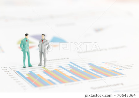 Miniature figures businessman standing on a graph chart Miniature figures businessman standing on a graph chart 70645364