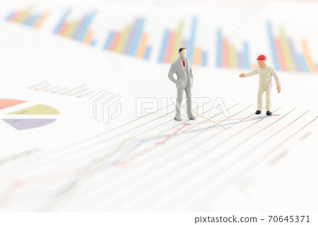 Miniature figures businessman standing on a graph chart Miniature figures businessman standing on a graph chart 70645371