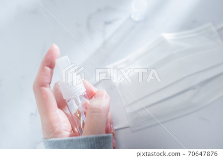 A state of holding a portable disinfectant spray in the room. 70647876