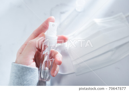 A state of holding a portable disinfectant spray in the room. 70647877