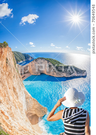 Woman with hat watching Navagio beach with shipwreck on Zakynthos island in Greece 70649548