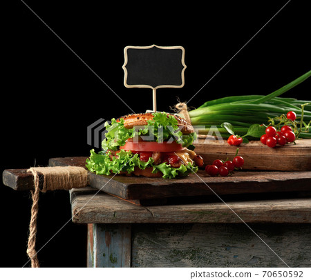 cheeseburger with minced meat, green lettuce and ketchup on a wooden brown kitchen board cheeseburger with minced meat, green lettuce and ketchup on a wooden brown kitchen board 70650592