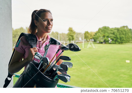 Contented female athlete holding a golf bag Contented female athlete holding a golf bag 70651270