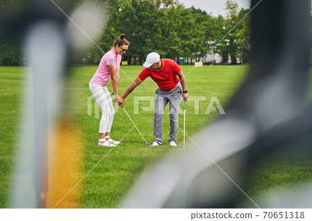 Smiling beginner golfer training with her personal coach Smiling beginner golfer training with her personal coach 70651318