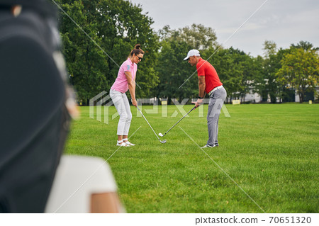 Two adult players perfecting their golf grips Two adult players perfecting their golf grips 70651320