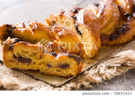 Homemade braid stuffed with chocolate and cut into pieces on wooden table. 70651423