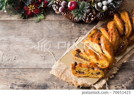 Homemade braid stuffed with chocolate and cut into pieces on wooden table. 70651425