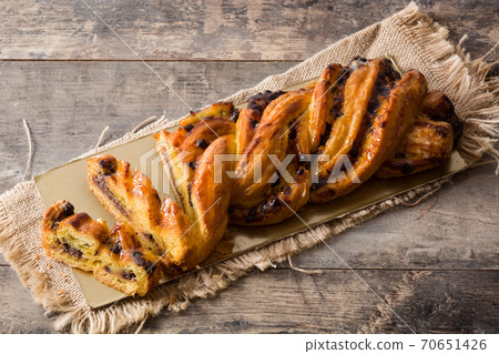 Homemade braid stuffed with chocolate and cut into pieces on wooden table. 70651426