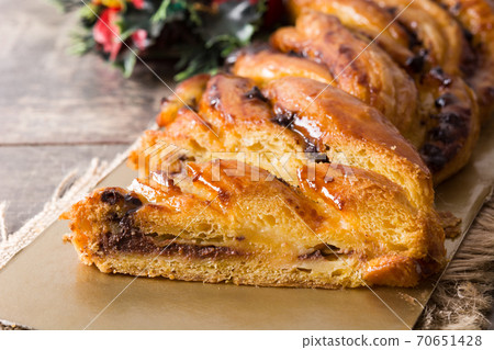 Homemade braid stuffed with chocolate and cut into pieces on wooden table. 70651428