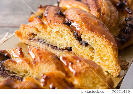 Homemade braid stuffed with chocolate and cut into pieces on wooden table. 70651429