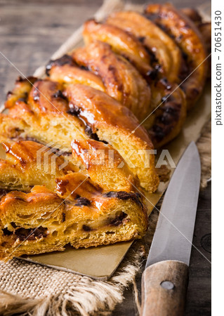 Homemade braid stuffed with chocolate and cut into pieces on wooden table. 70651430