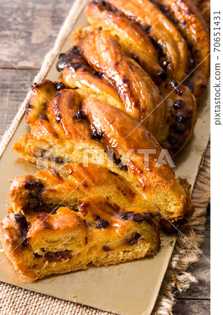 Homemade braid stuffed with chocolate and cut into pieces on wooden table. 70651431