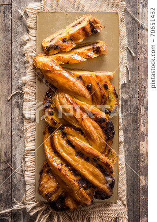 Homemade braid stuffed with chocolate and cut into pieces on wooden table. 70651432